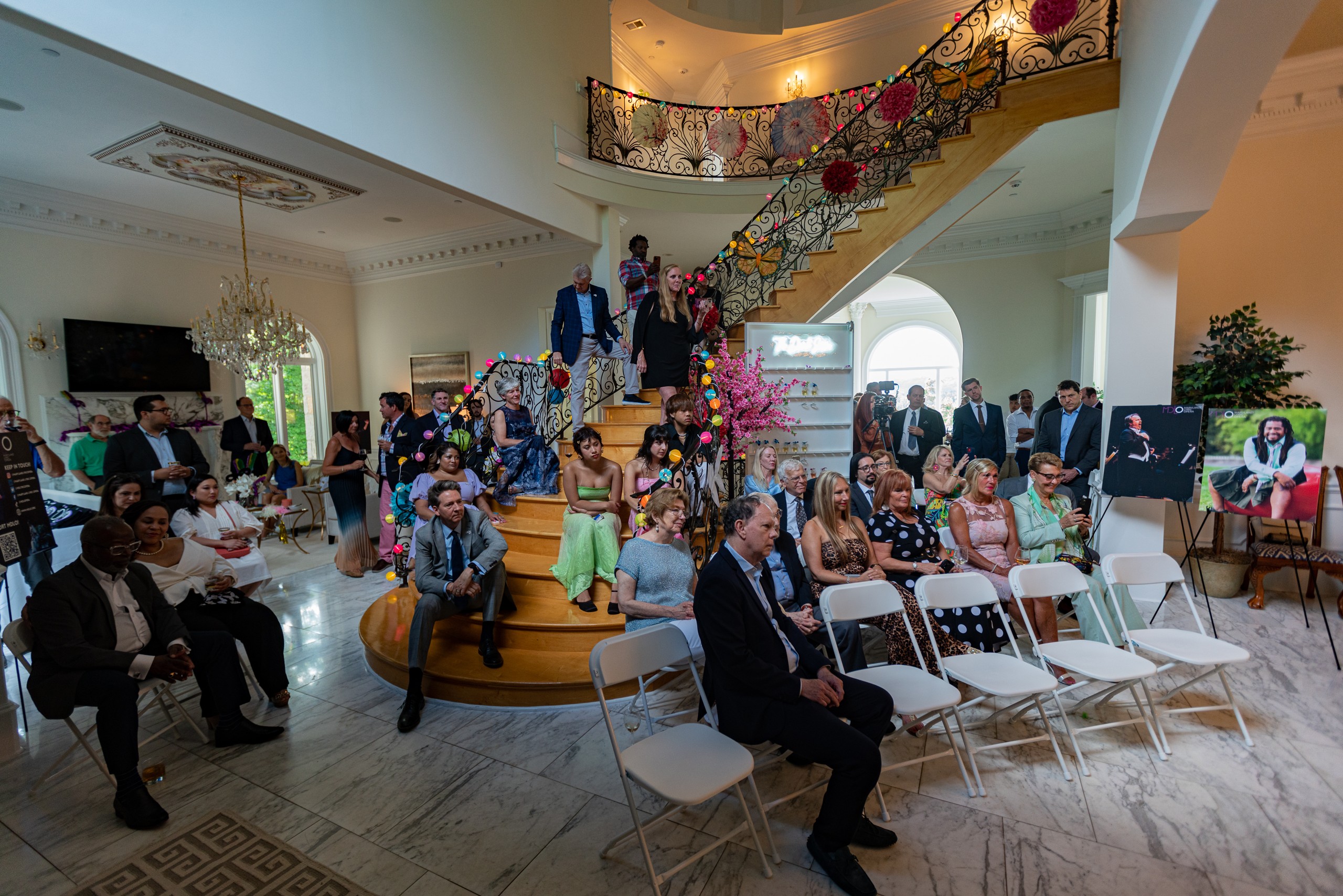 A seated audience gathered around the grand staircase for live music