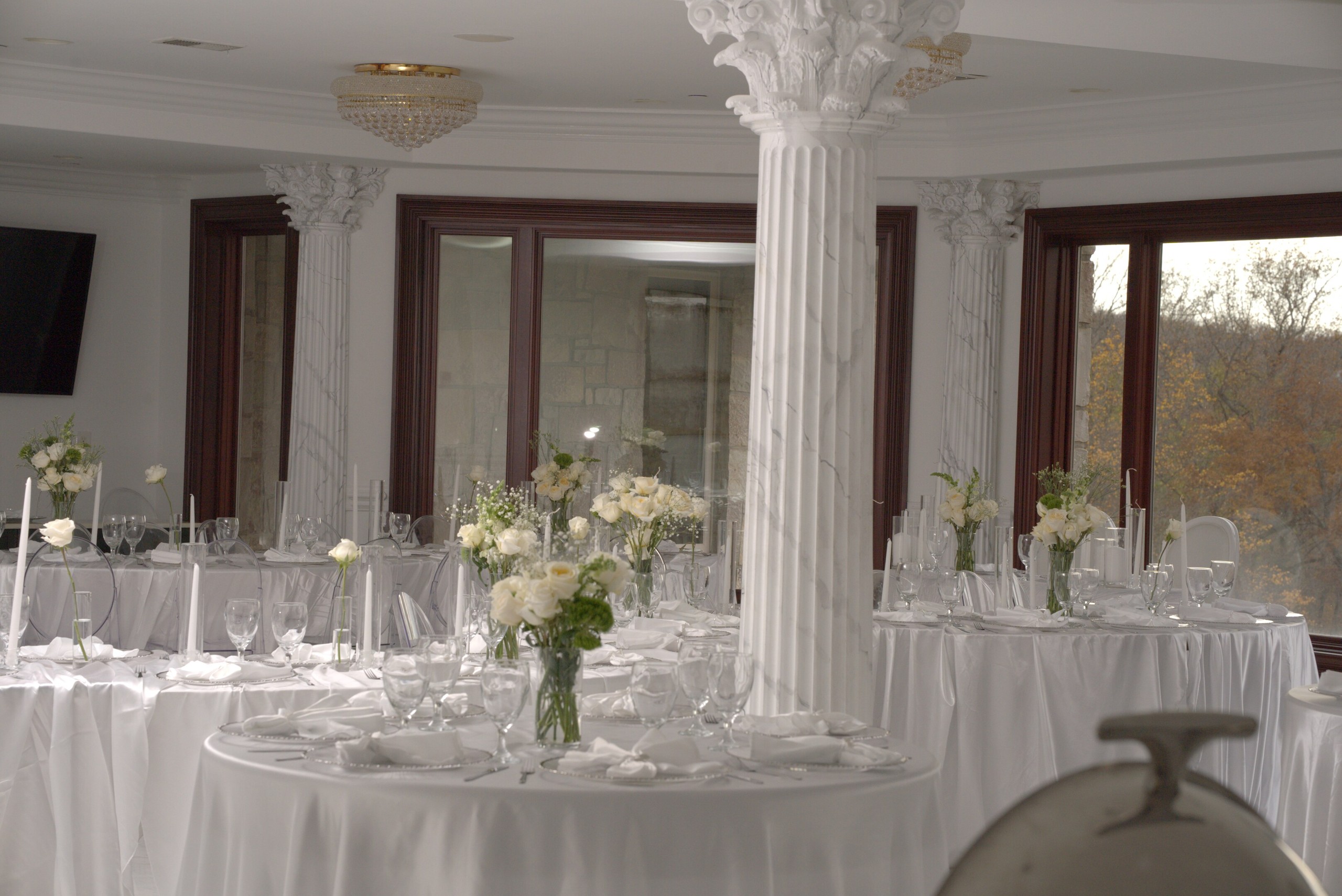 Grand ballroom arranged with white floral centerpieces and dressed dining tables
